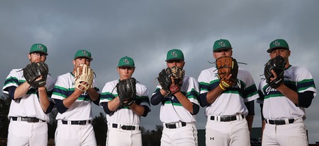 Several members of the baseball team pose with gloves in front of their faces for a group photo.