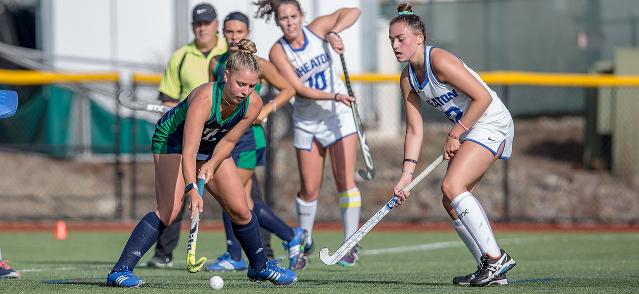 Two field hockey players battle for a loose ball.