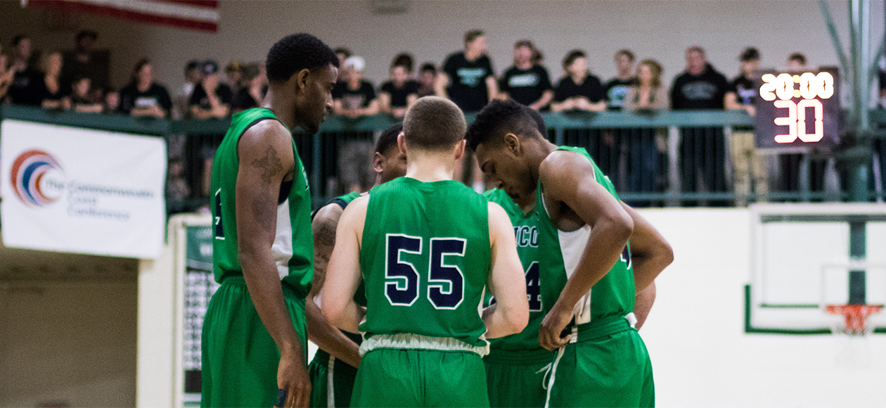 The Endicott men's basketball team huddles up on the court.