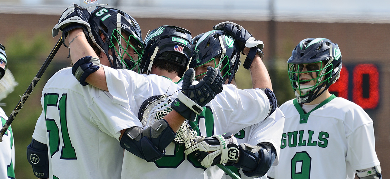 Members of the Endicott men's lacrosse team huddle up and celebrate after scoring a goal.