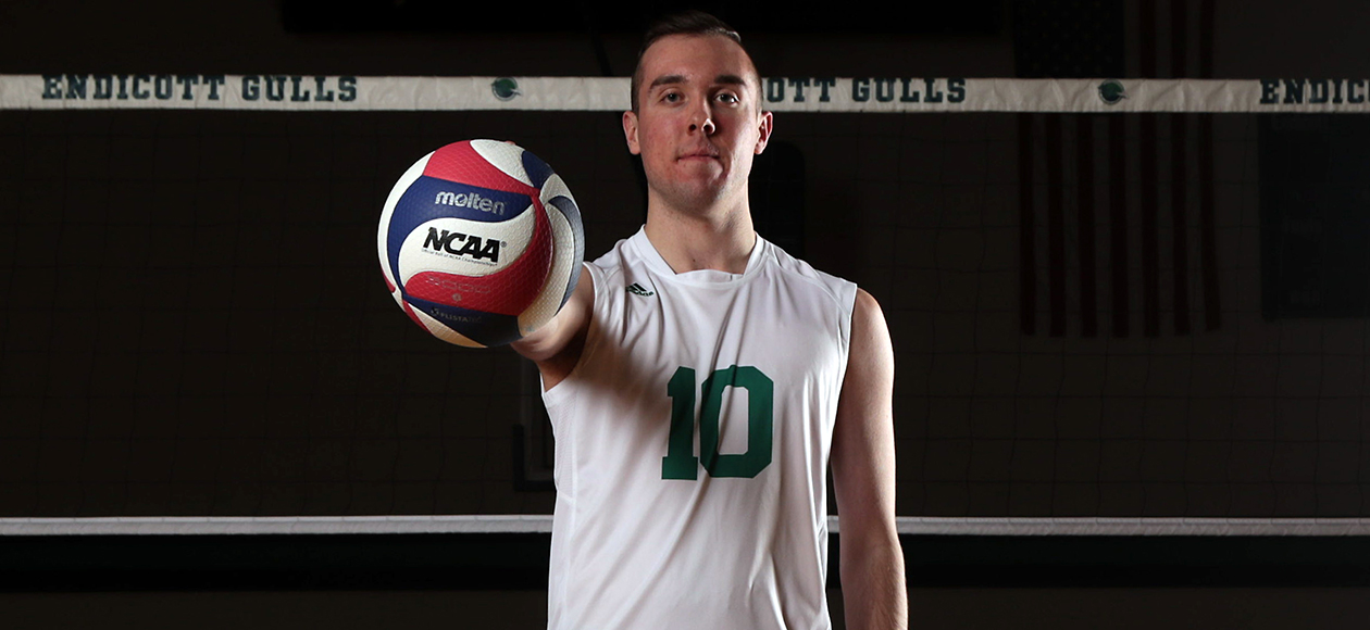 Matt Bozek holds a volleyball in front of his chest.