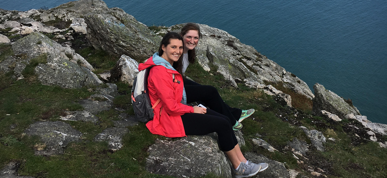 Image of Molly McMahon and Erin Gill sitting on the cliffs overlooking the ocean in Ireland.