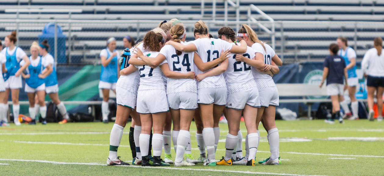 Image of the women's soccer team huddled before a match begins.