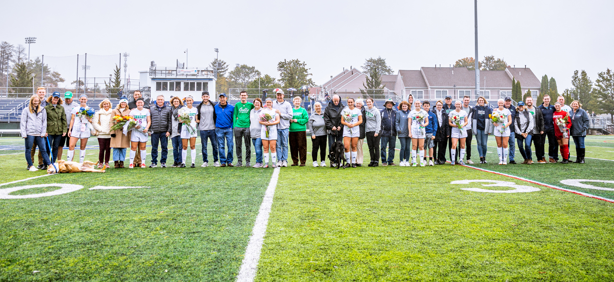 Image of all nine Endicott women's soccer seniors and their families on the field for the pre-game celebration.
