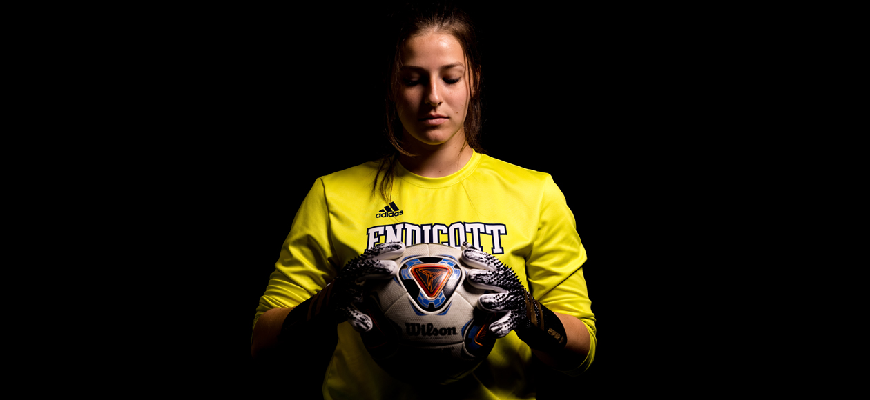 Staged photo of Jacqueline Ruggiero looking down at a soccer ball held in her two hands.