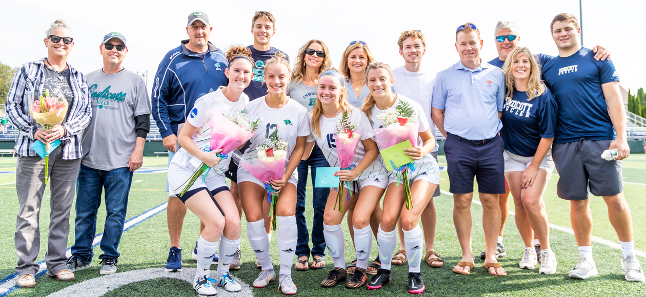 Picture of the four Endicott seniors and their families on the field.