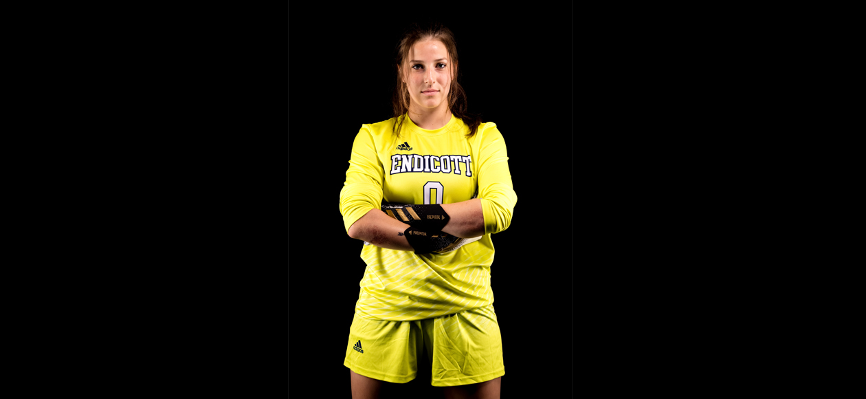 Staged photo of Jacqueline Ruggiero standing with her arms folded across her chest, in her yellow keeper's kit.
