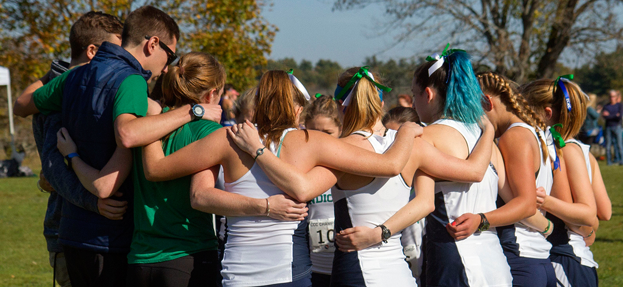 The Endicott women's cross country team forms a huddle before a race.