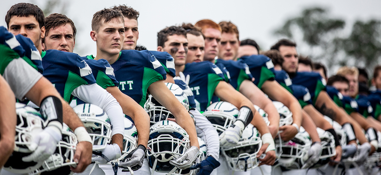 Members of the Endicott football team stand in line during the national anthem.