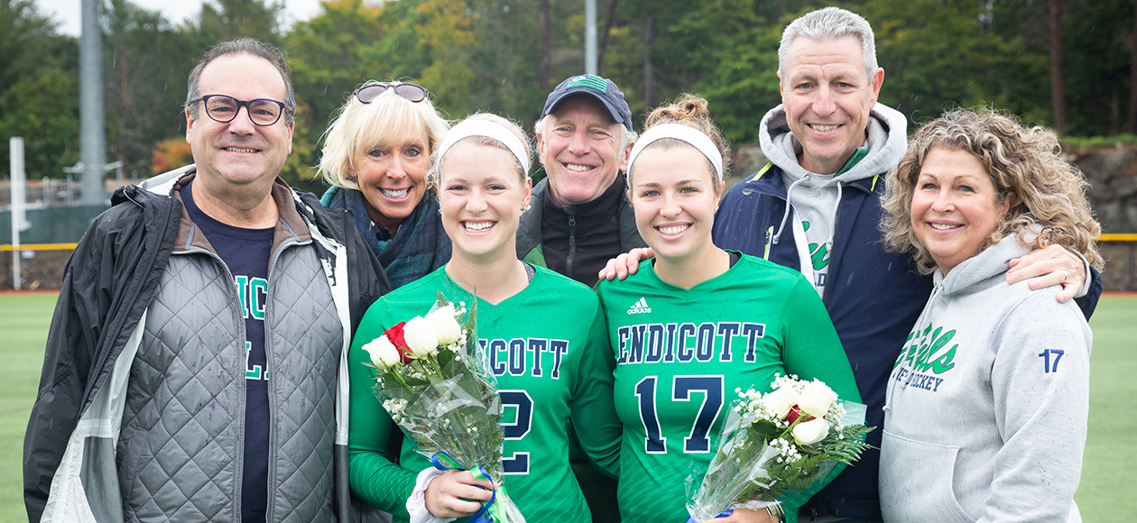 Cami Mollinare and Maggie O'Reilly pose with their families for a photo on Senior Day.