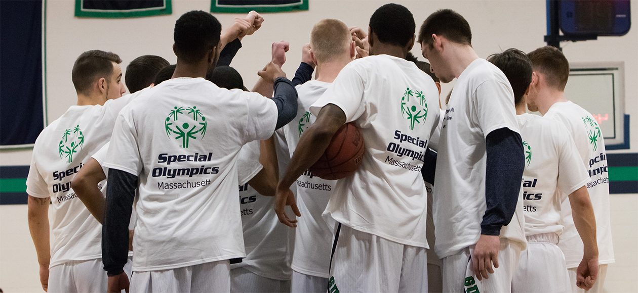 The Endicott men's basketball team breaks a huddle wearing their white Special Olympics t-shirts.