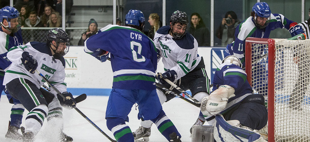 Student-athletes on the Endicott men's ice hockey team battle for the puck in front of the net.
