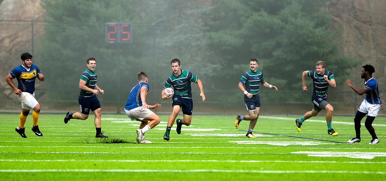 A men's rugby student-athlete tries to run by a defender.