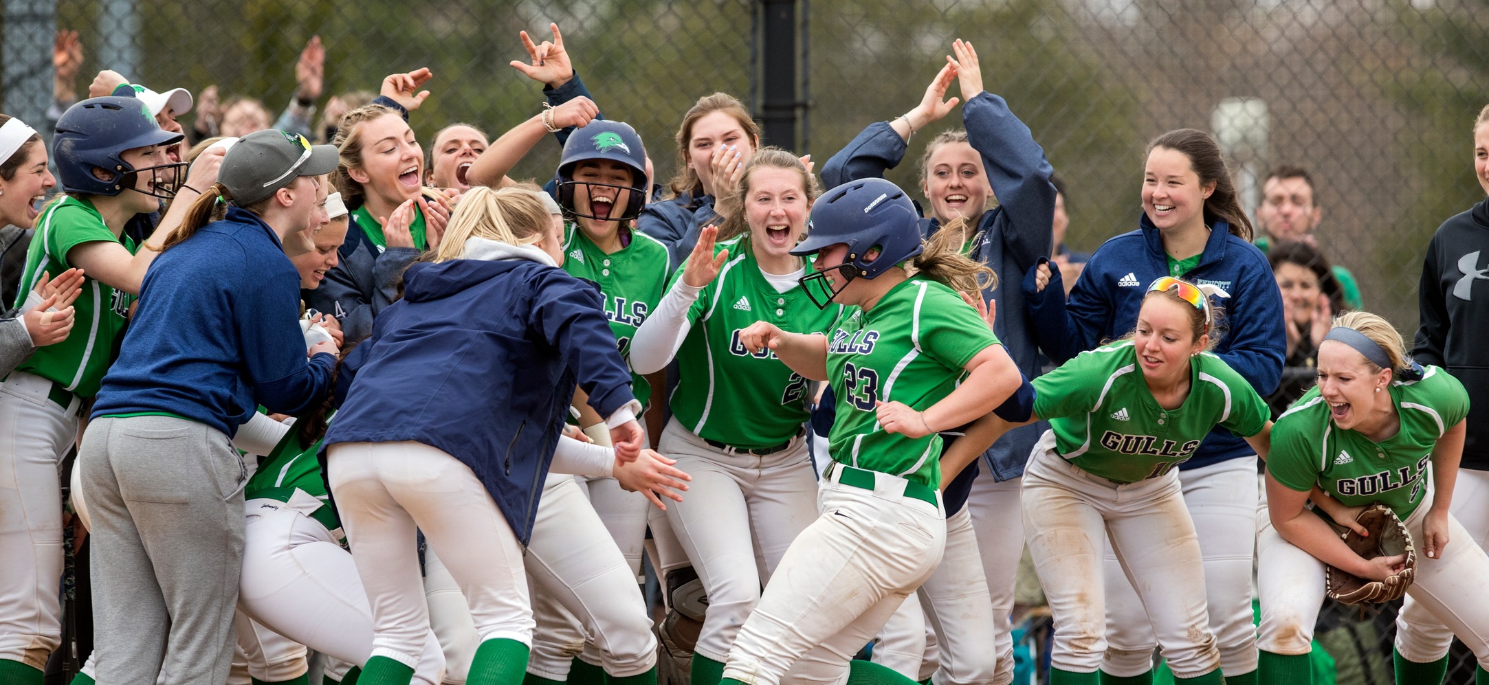 Hayley Arduini crosses home plate after a home run as her teammates celebrate around her. 