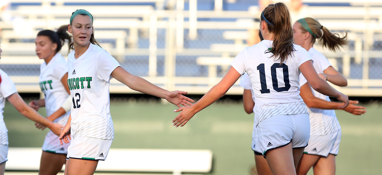 Women's soccer players celebrate.