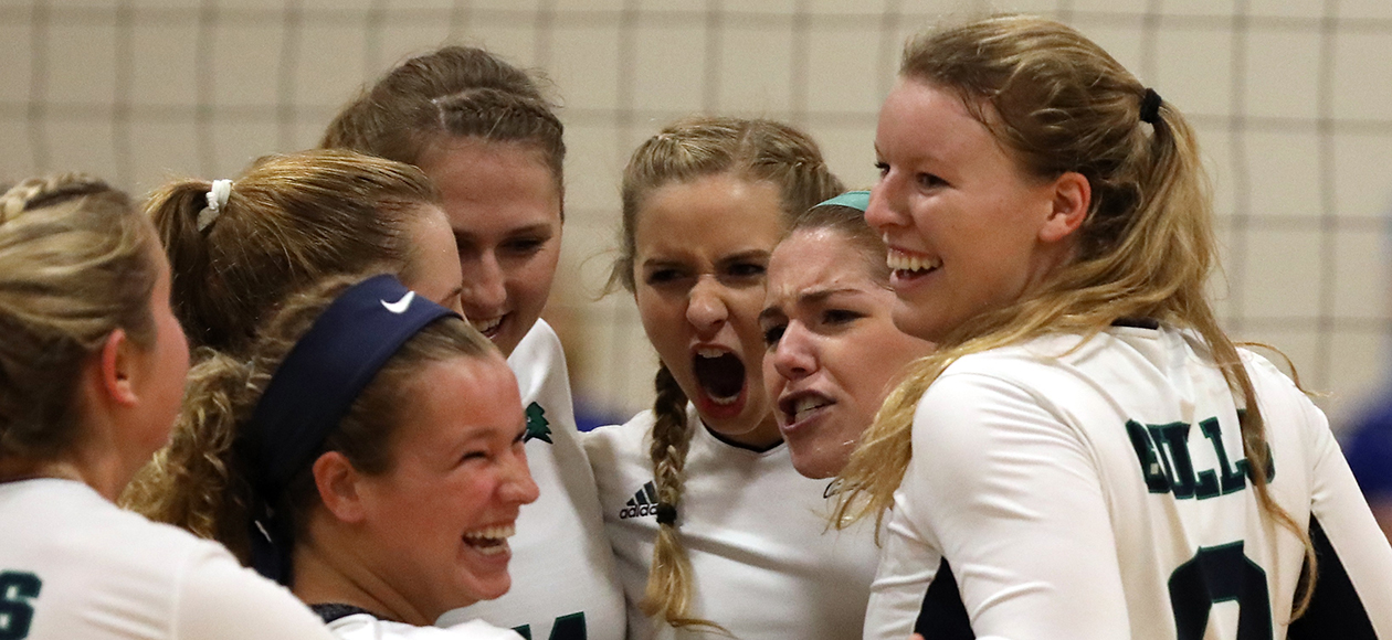 The women's volleyball team celebrates in a huddle after their thrilling victory over UMass Boston.
