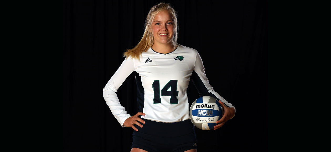 Meghan Frederick poses for a photo with a volleyball at her hip.
