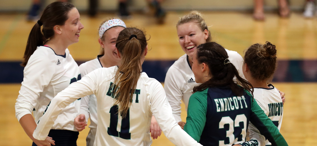 Image of the Endicott women's volleyball team huddled on the court.